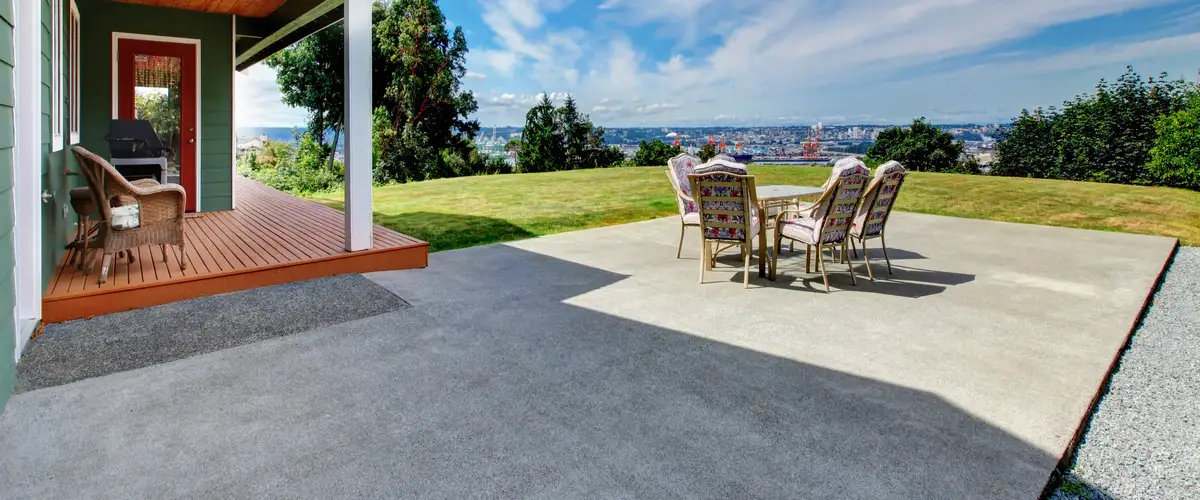 A spacious outdoor patio area with outdoor dining furniture and a scenic water view, featuring smooth concrete resurfacing.