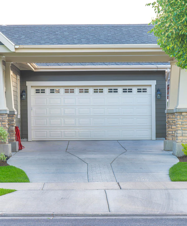 A freshly finished driveway showing recent concrete resurfacing leading up to a home with a white garage door in Powell, TN.
